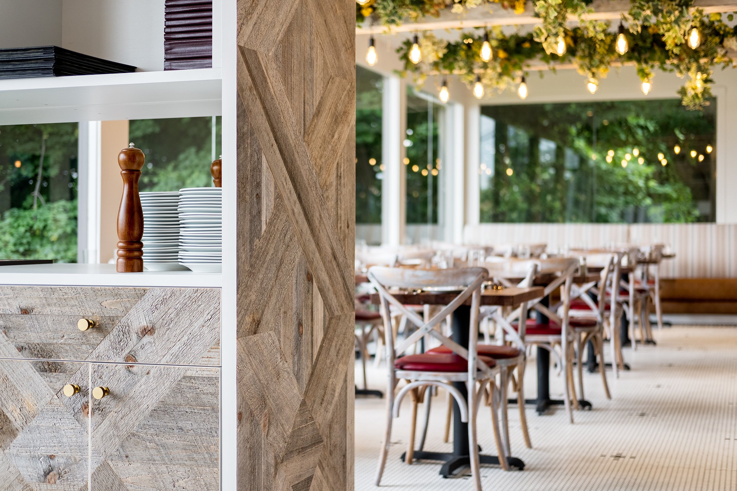 Dining room tables prepared before service with soft lights and warm wood details.