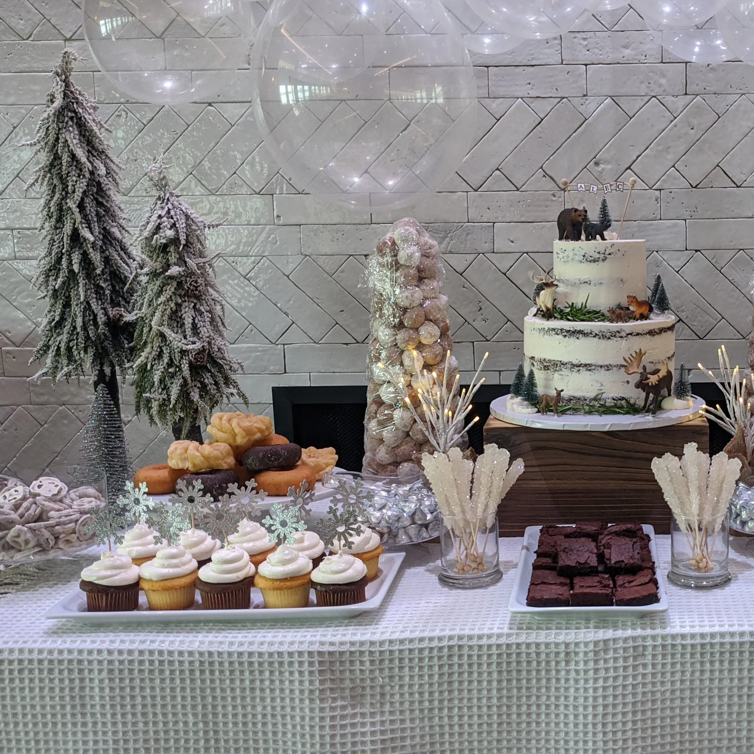 A celebration dessert table at DeNovo Edgewater with cake, cupcakes, and white balloons.