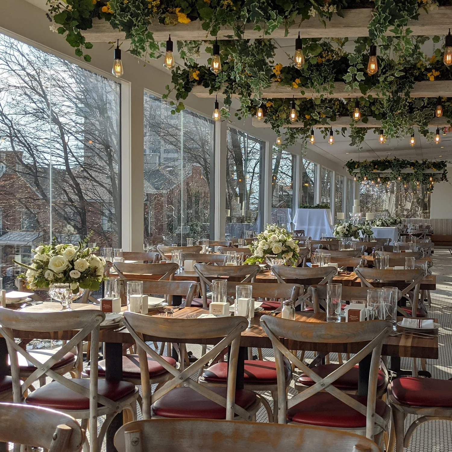 A holiday party table setup at DeNovo Edgewater with greenery, string lights, and white floral centerpieces.