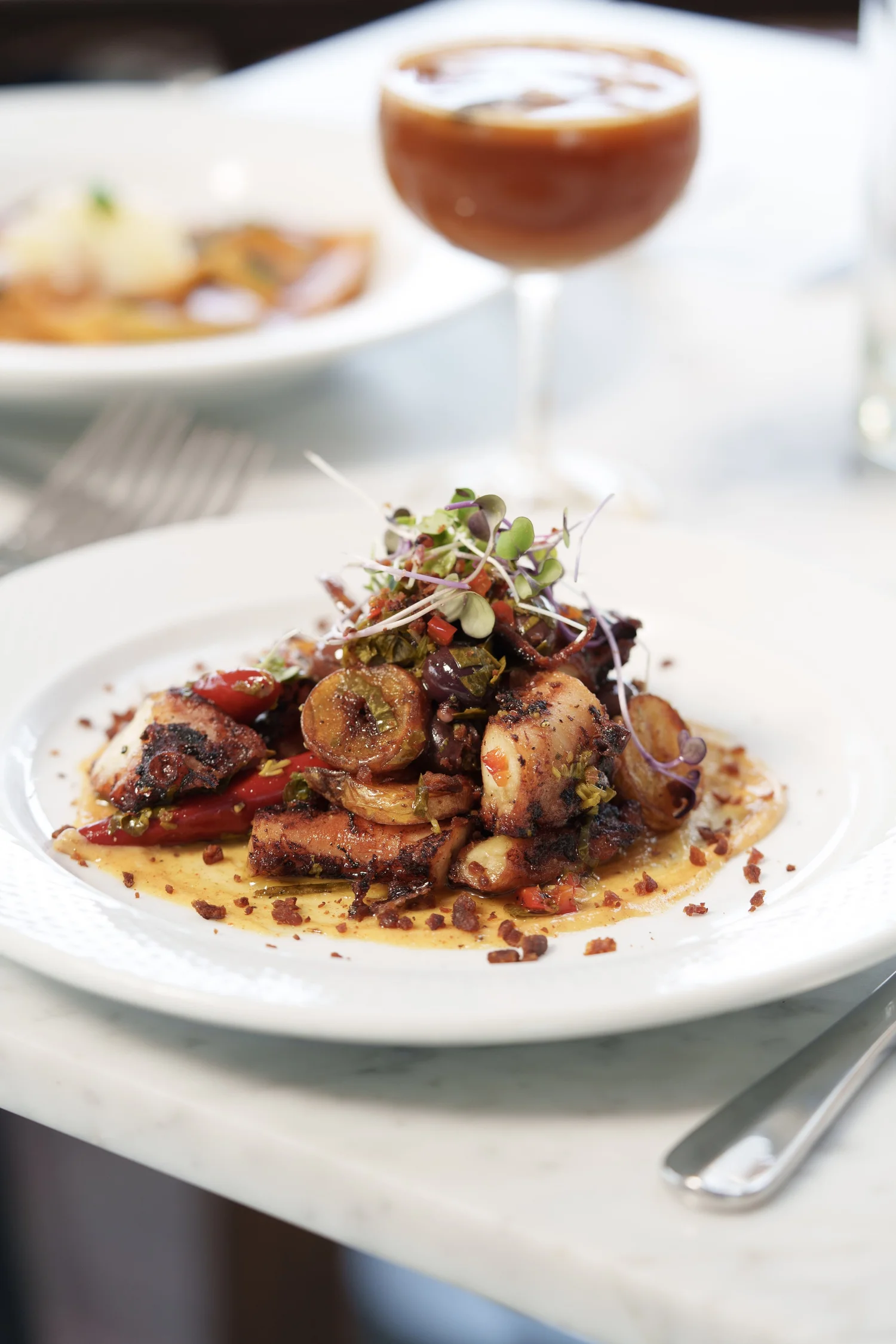 Grilled octopus with chorizo and salsa verde on a dark plate.