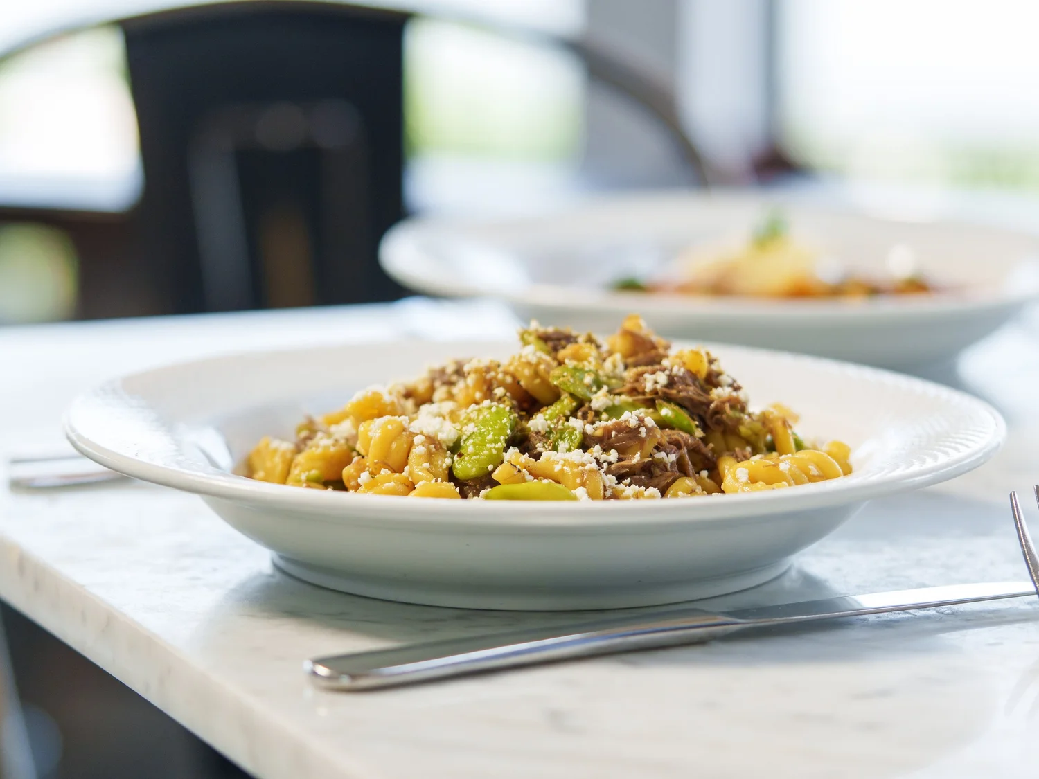 Hand-rolled pappardelle with short rib ragù in a white bowl.