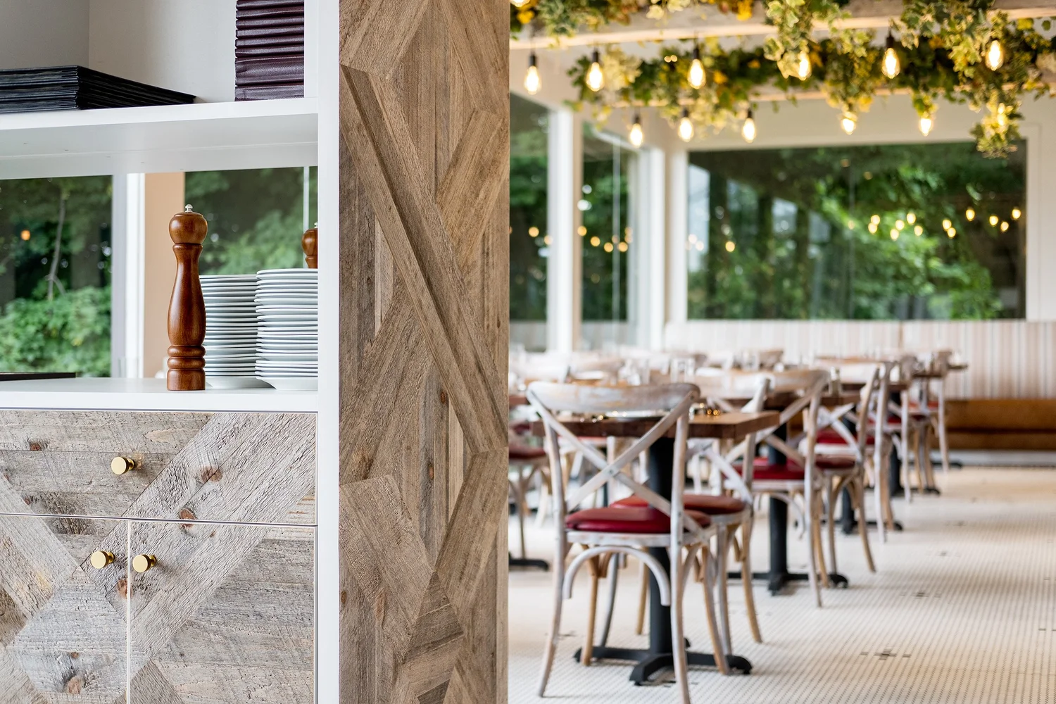 A detail of the DeNovo dining room with white shelving, stacked plates, and a herringbone wood column.
